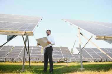 Solar power plant. Man standing near solar panels. Renewable energy.