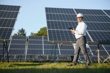 Solar power plant. Man standing near solar panels. Renewable energy.