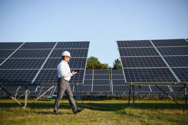 Güneş paneli çiftliğinde çalışan kıdemli mühendis. Yeşil enerji kavramı.