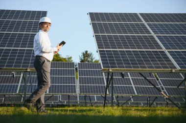 Solar power plant. Man standing near solar panels. Renewable energy.