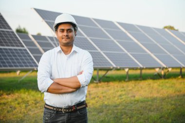 Güneş paneli çiftliğindeki genç Hintli erkek mühendis ya da mimarın portresi. Temiz enerji kavramı.