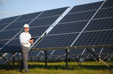 Erkek mühendis çiftlikteki güneş panellerini inceliyor. Temiz enerji