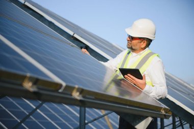 Erkek mühendis çiftlikteki güneş panellerini inceliyor. Temiz enerji