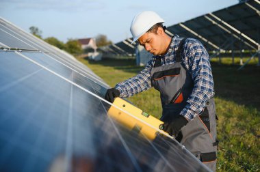 Hintli bir erkek işçi bir tarlaya güneş panelleri yerleştirmeye çalışıyor..