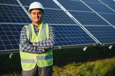 Erkek Arap mühendis güneş panellerindeki direnci kontrol ediyor. İstasyonda çalışan Hintli adam..