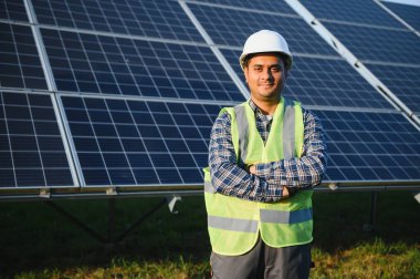 Güneş çiftliğinde üniformalı bir Hintli. Yetkin enerji mühendisi fotovoltaik hücrelerin çalışmalarını kontrol ediyor.