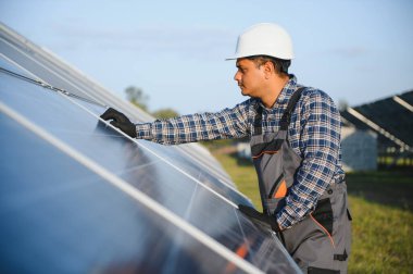 Güneş çiftliğinde üniformalı bir Hintli. Yetkin enerji mühendisi fotovoltaik hücrelerin çalışmalarını kontrol ediyor.