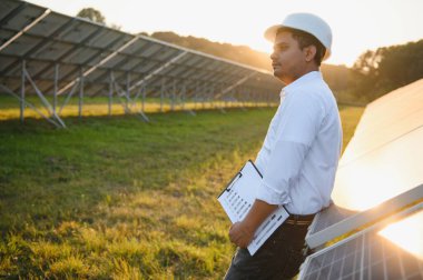 Güneş paneli çiftliğindeki genç Hintli erkek mühendis ya da mimarın portresi. Temiz enerji kavramı.