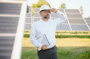 Solar power plant. Man standing near solar panels. Renewable energy.