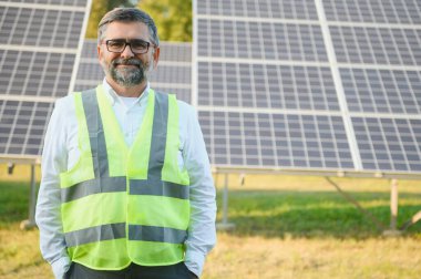 Güneş paneli çiftliğinde çalışan kıdemli mühendis. Yeşil enerji kavramı.