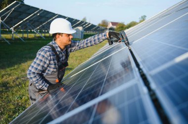 Üniformalı ve aletleri olan Hintli bir işçi güneş paneli çiftliğinde çalışıyor..