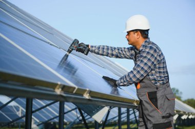 Üniformalı ve aletleri olan Hintli bir işçi güneş paneli çiftliğinde çalışıyor..