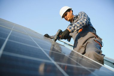 Üniformalı ve aletleri olan Hintli bir işçi güneş paneli çiftliğinde çalışıyor..