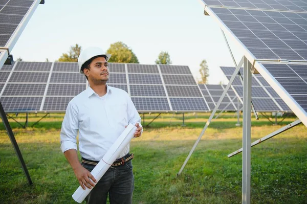 Portrait of a young Indian male engineer or architect at a solar panel farm. The concept of clean energy.