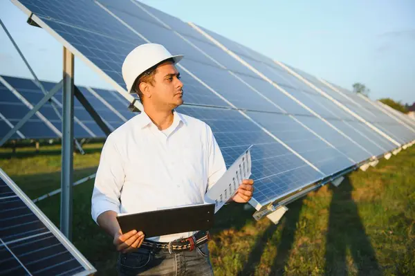 Portrait young indian technician or manager wearing formal cloths standing with solar panel. renewable energy, man standing crossed arm, copy space.