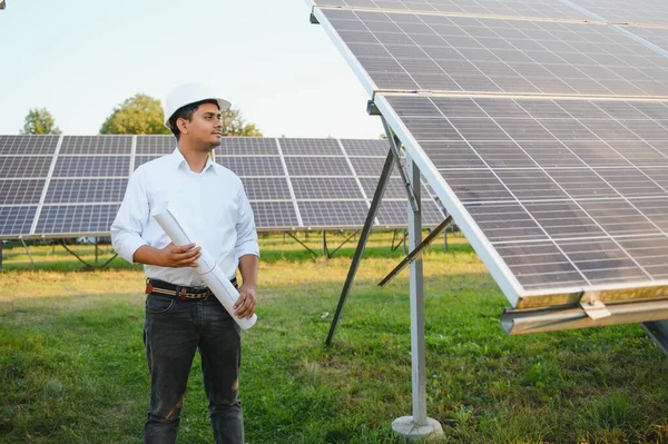Portrait young indian technician or manager wearing formal cloths standing with solar panel. renewable energy, man standing crossed arm, copy space.