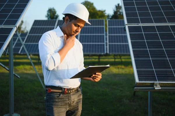 Portrait of Young indian male engineer standing near solar panels, with clear blue sky background, Renewable and clean energy. skill india, copy space.