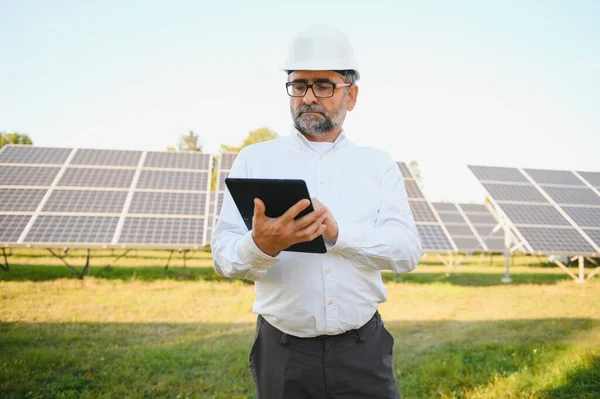 Senior engineer working on solar panel farm. The concept of green energy.