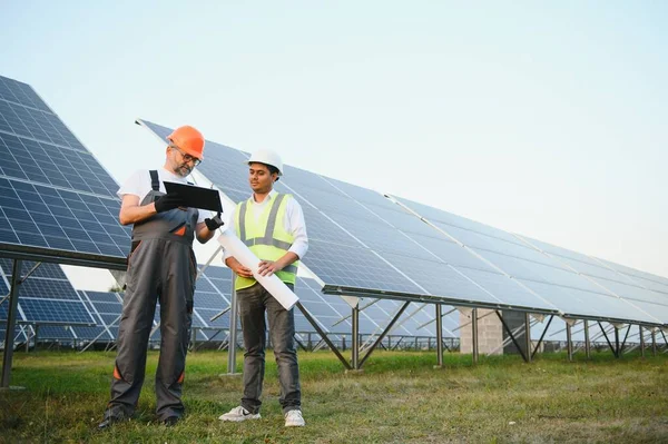 Two male engineers Currently working on plans to install solar panels at renewable solar power plants. Engineer team talks about installing solar cells on rural areas.