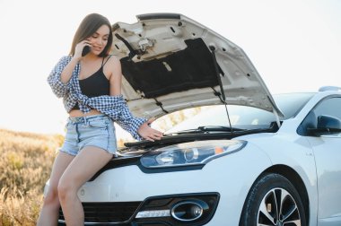 Genç, güzel, seksi bir kadın. Bozuk arabasında, cep telefonuyla yolda dikiliyor, cep telefonuyla yardım istiyor..