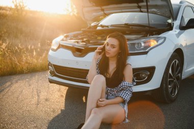 Kırık arabalı genç seksi kadın cep telefonundan arıyor.