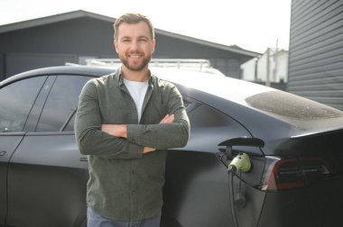 Evin yanında elektrikli araba şarj eden bir adam var..