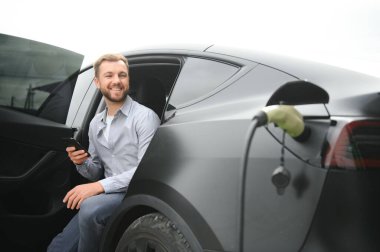 Evin yanında elektrikli araba şarj eden bir adam var..