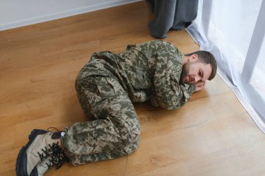 Asker evde yerde depresif bir şekilde yatıyor. PTSD.