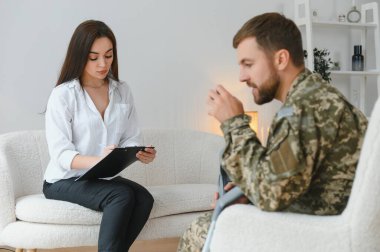 Psikolog üzgün erkek asker, Ptsd ile terapi oturumu sırasında notlar yapma.