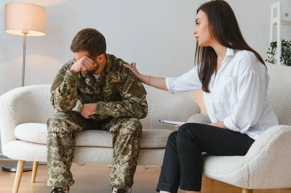 Sad male soldier on appointment with psychologist at office.