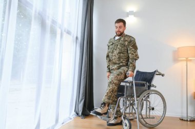 Askeri üniformalı mutlu asker tekerlekli sandalyeden kalkıyor. Gazilerin rehabilitasyonu kavramı.