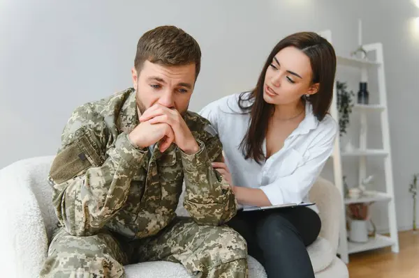 Sad male soldier on appointment with psychologist at office.
