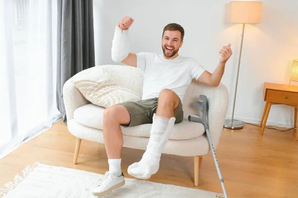Happy man recovery from accident fracture broken bone injury with leg and arm. Social security and health insurance concept.