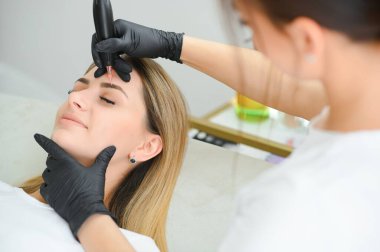 Kalıcı kaş makyajı prosedürü sırasında genç bayan, yakın çekim.