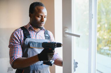 Afrikalı Tamirci Balkondaki Kırık Pencereyi Tamir Ediyor.