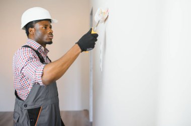 Genç erkek elektrikçi elektrik prizleri kuruyor ve değiştiriyor.