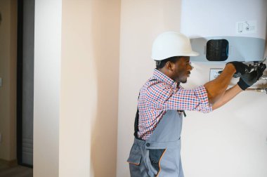 Afrikalı Amerikalı işçi evde merkezi gaz ısıtıcısı kurmuş..