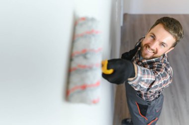 Boyacı duvarı boyuyor, boya silindiriyle..