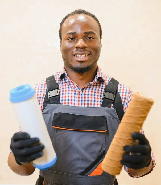 African American plumber holding new and used water filters.