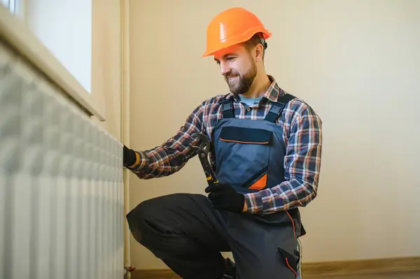 Plumber man is blocking repairs radiators of heating battery in apartment tap.