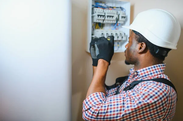 African american electrician Repairing electricity switchboard.