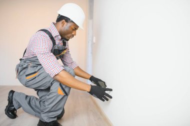 Genç erkek elektrikçi elektrik prizleri kuruyor ve değiştiriyor.