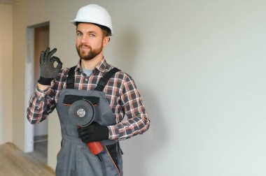 İnşaat alanında çalışırken genç ve yakışıklı bir inşaatçının portresi.