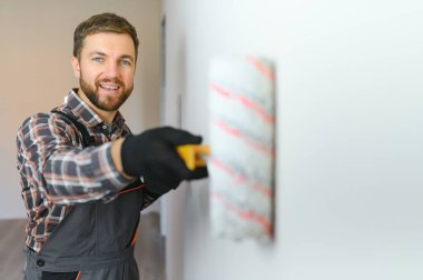 Boyacı duvarı boyuyor, boya silindiriyle..