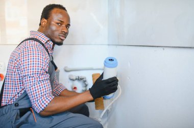 Afrika kökenli Amerikalı Tesisatçı su filtresi yükler ya da değiştirir. Yerleştirme su filtresi.
