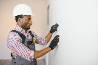 Afrikalı-Amerikalı elektrikçi odada soket voltaj düzenleyicisi kullanıyor..