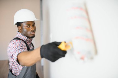 Afro-Amerikalı dekoratör ışık duvarı boyuyor.