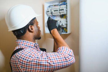 Bir erkek elektrikçi elektrik kablosuyla santralde çalışıyor..