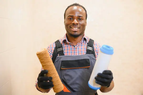 African American plumber holding new and used water filters.