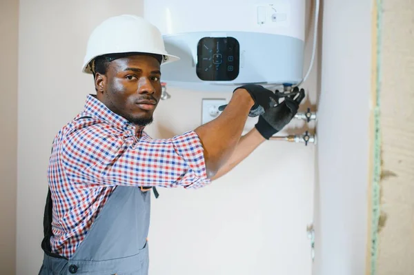 African american worker set up central gas heating boiler at home.